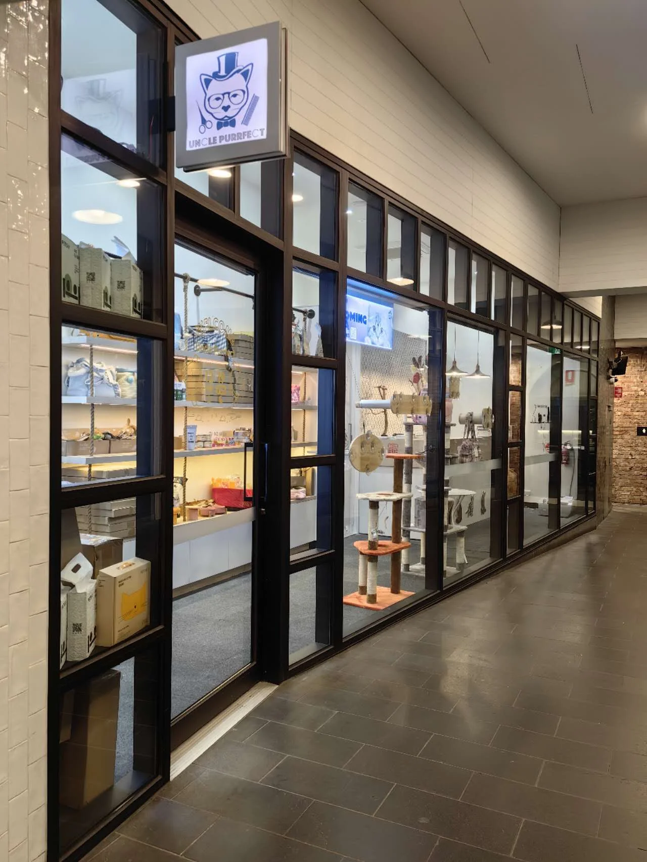 Uncle Purrfect's Spencer St storefront — glass cabinets of premium product and the illuminated gentleman sign